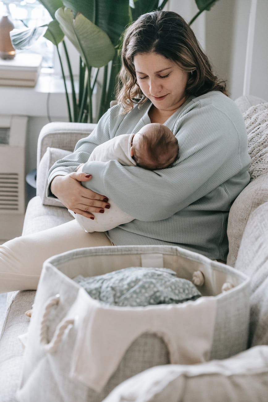 mother with newborn baby on couch, postpartum recovery