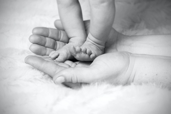birth trauma, newborn feet in mothers hands